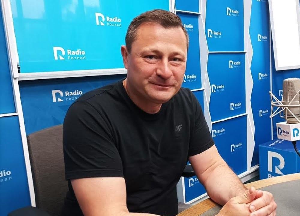 Krzysztof Paszyk, minister rozwoju i technologii, w dynamicznej pozie na tle symbolizującym innowacje i nowoczesne technologie.