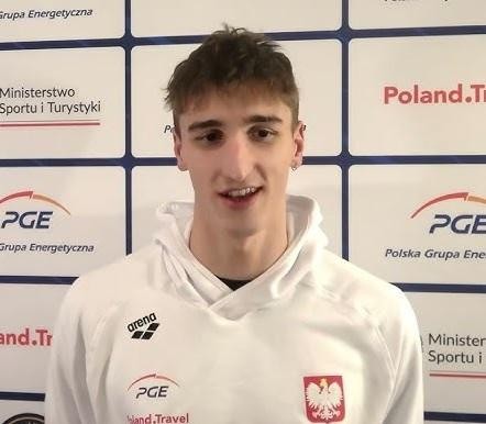 Ksawery Masiuk w pełnym ujęciu podczas pływania stylem grzbietowym, ukazujący jego technikę i atletyczną budowę ciała.