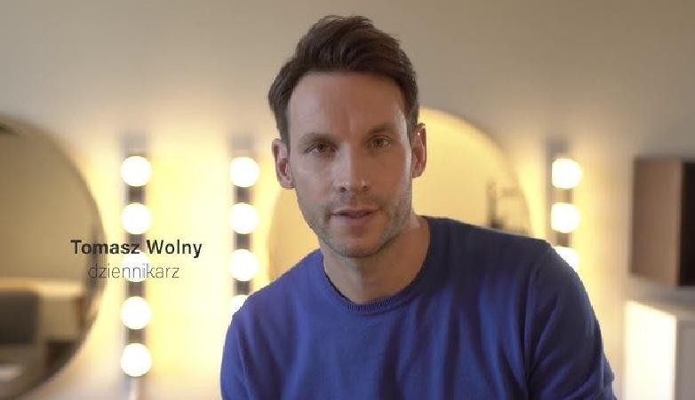 Tomasz Wolny w otoczeniu dzieci podczas wydarzenia charytatywnego, uśmiechnięty i zaangażowany.