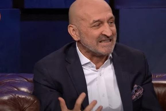 Kazimierz Marcinkiewicz w rękawicach bokserskich, w trakcie charytatywnej walki bokserskiej, z widownią w tle, ukazujący jego zaangażowanie w akcje dobroczynne.