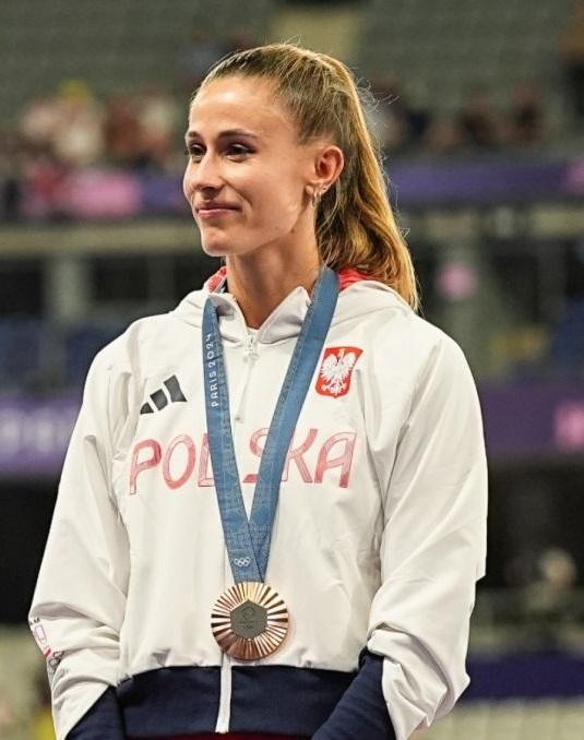Natalia Bukowiecka, polska lekkoatletka, odbierająca odznaczenie państwowe lub medal, uśmiechnięta i dumna.