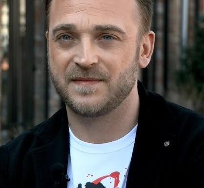Mateusz Gessler podczas gotowania w profesjonalnej kuchni, w tle widoczne elementy restauracyjne.