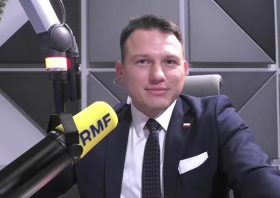 Sławomir Mentzen podczas wiecu politycznego, dynamicznie przemawiający do publiczności, z widocznym hasłem 