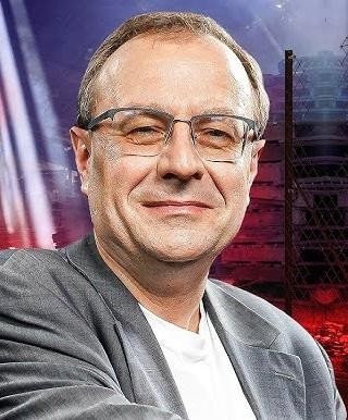 Antoni Dudek podczas wystąpienia publicznego lub nagrania, symbolizujący jego rolę historyka, politologa i publicysty.