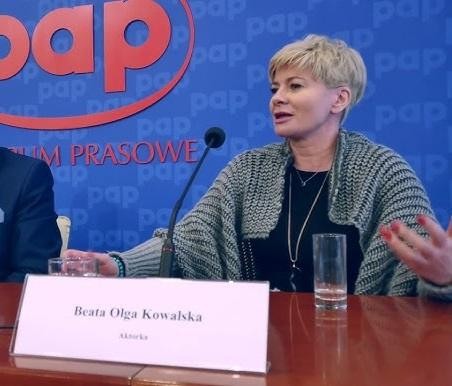 Beata Olga Kowalska w dynamicznej scenie na scenie lub podczas występu telewizyjnego, ukazująca jej energię i ekspresję artystyczną.