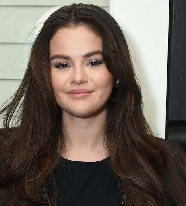 Selena Gomez w interakcji z fanami, uśmiechnięta, w tle publiczność, symbolizująca jej zaangażowanie w promowanie zdrowia psychicznego.