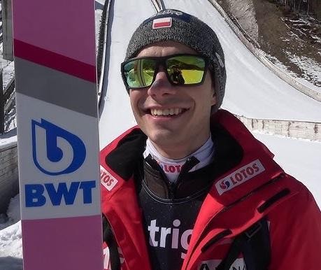 Jakub Wolny w stroju skoczka narciarskiego, ujęcie z bliska, z subtelnym rozmyciem tła, symbolizujące jego aktywność w mediach społecznościowych.